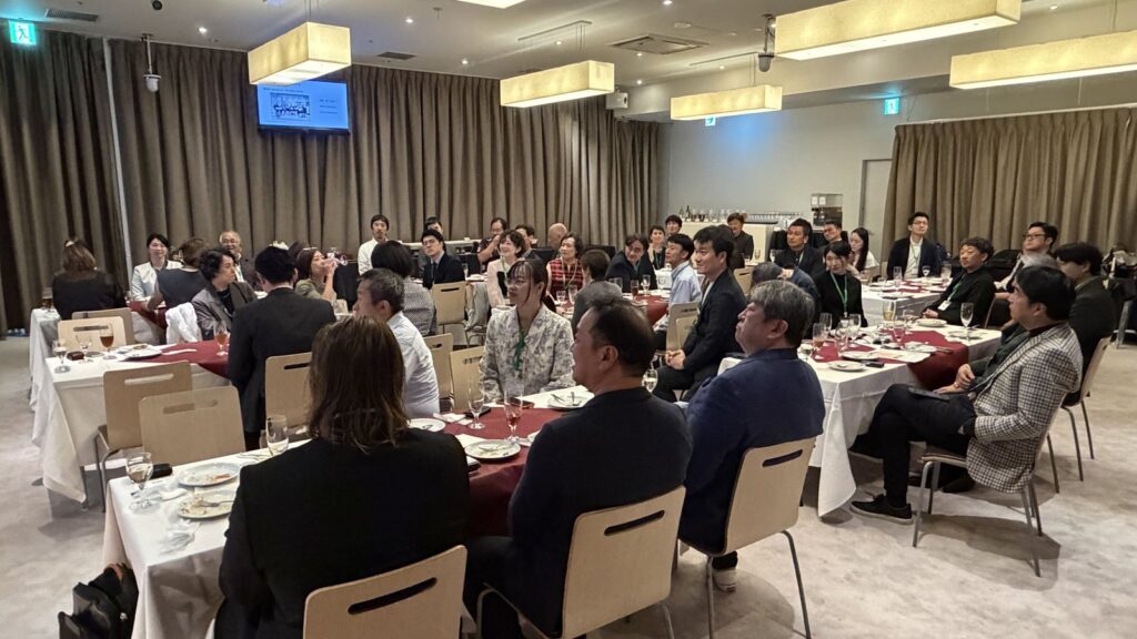 Full view of the GSJ 6th anniversary party venue, with guests seated at round tables facing the stage